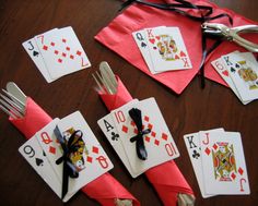 the table is set with playing cards and utensils