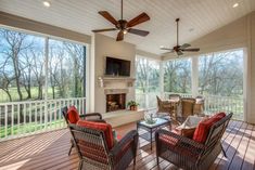 a covered porch with wicker furniture and ceiling fans