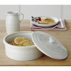 a pan with pancakes in it sitting on a table next to a pitcher and bowl