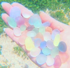 small pieces of sea glass sitting on the palm of someone's hand under water