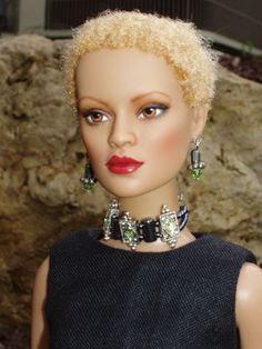 a mannequin head with blonde hair and green earrings on it's neck