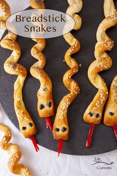 breadsticks are arranged in the shape of snakes on a black plate with red peppers