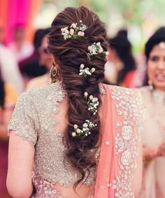 a woman in a bridal gown with flowers in her hair and another woman standing behind her