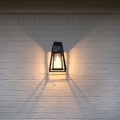 a lamp on the side of a white brick wall