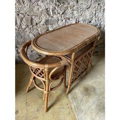 two wicker chairs and table in front of a stone wall, with one sitting on the floor