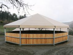 a large white tent sitting on top of a dirt field next to a wooden fence