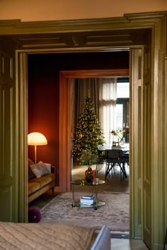 an open door leading to a living room with a christmas tree in the corner and a couch