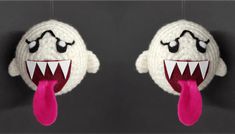 two stuffed toys hanging from strings with mouths open and tongues out, both wearing knitted sweaters