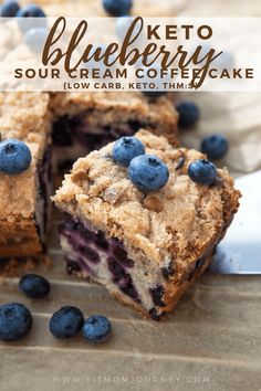 blueberry crumb cake cut in half on a cutting board with fresh blueberries