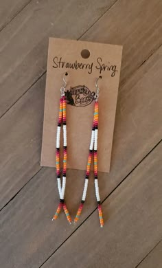 the beaded earrings are on display in front of a card that says strawberry string