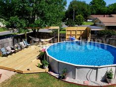 an above ground swimming pool with deck and lounge chairs around it in a backyard area