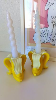 two yellow and white vases sitting next to each other on top of a table