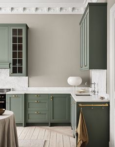 a kitchen with green cabinets and white counter tops, along with a round dining table