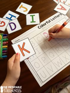 a child's hand is writing letters on a sheet of paper