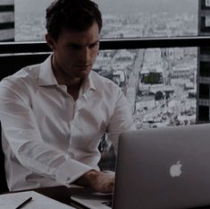 a man sitting at a table using a laptop computer