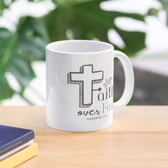 a white coffee mug sitting on top of a wooden table next to a blue book