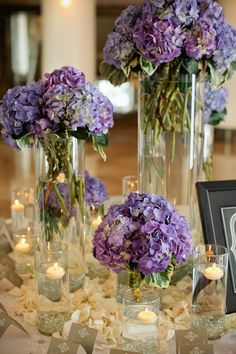 there are many vases with flowers in them on the table and candles around it