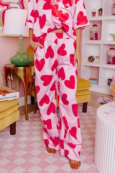 - Get your beauty sleep in these sweet pajama pants! - Unlined material with a pink heart print and accent piping - An elastic waistline - Functional side pockets - A relaxed silhouette that ends in straight hemline Formal Dress Jacket, Southern Belle Style, Satin Pajama Pants, Heart Prints, Plus Size Pajamas, Heart Themed, Heart Valentines, Beauty Sleep, Pink Valentines