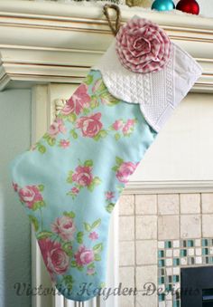 a christmas stocking hanging from a fireplace mantel decorated with pink and green flowers