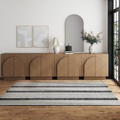 a living room with a rug, mirror and vases on the sideboard in front of it