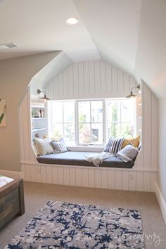 a window seat in the corner of a room with a blue rug on the floor