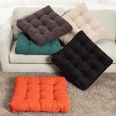 four different colored cushions sitting on top of a white couch