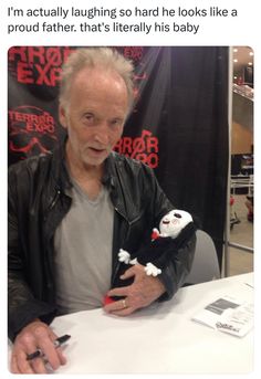 an older man sitting at a table with a doll in his hand and the caption reads, i'm actually laughing so hard he looks like a proud father, that's literally his baby