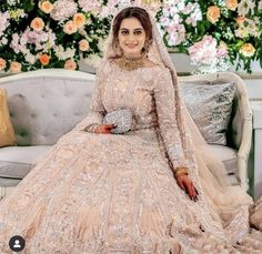 a woman sitting on top of a couch wearing a wedding dress and veil with flowers in the background