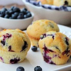 blueberry muffins on a white plate with bowls of blueberries in the background