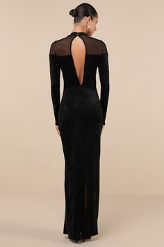 the back of a woman wearing a black velvet gown with sheer sleeves and open shoulders