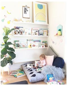 a small child is sitting on a bean bag chair in the corner of a room filled with books