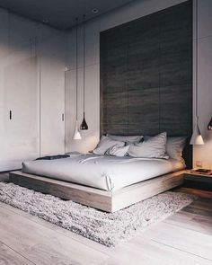 a large bed sitting on top of a wooden floor next to a wall mounted lamp