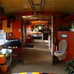 the interior of a bus with orange walls and red trim, including a toilet and sink