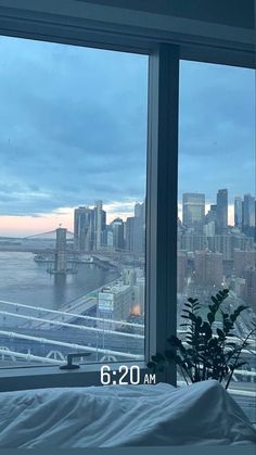 a window view of a city and the water from a bedroom in an apartment building