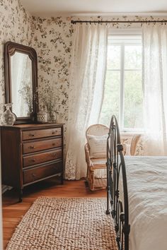 a bedroom with a bed, dresser and mirror next to a window in the room