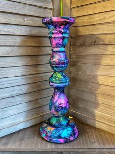 a multicolored vase sitting on top of a wooden table next to a wall