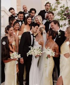 a group of people standing next to each other in front of a building with white flowers