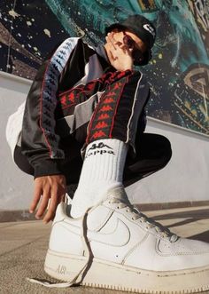 a man sitting on the ground wearing white sneakers