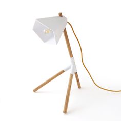 a white table lamp sitting on top of a wooden tripod with a cord attached to it