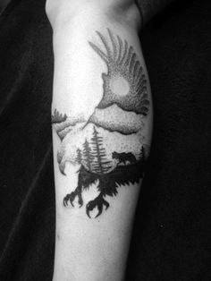 a person with a tattoo on their arm that has an eagle and bear in it