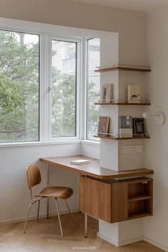 a desk and chair in front of two large windows with books on the ledges