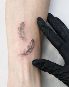 a small feather tattoo on the right arm and leg, next to a pair of gloves