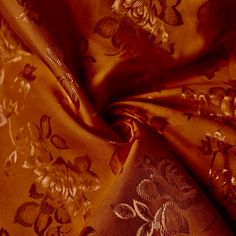 an orange and gold colored fabric with flowers on the side, in close up view