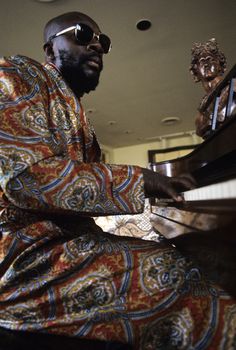 a man sitting at a piano in front of a busturine