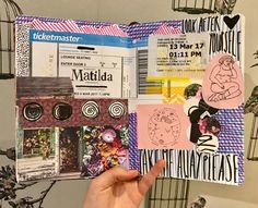 a person holding up a scrapbook with pictures and stickers on it, in front of a birdcage