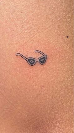 a woman's stomach with a small tattoo on the side of her stomach, which has an image of a pair of sunglasses