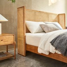 a bed sitting next to a night stand on top of a wooden table in a bedroom