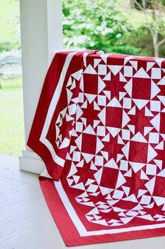 a red and white quilt sitting on top of a porch