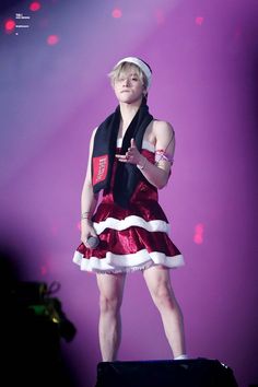 a woman in a red and white dress standing on stage with her hands out to the side