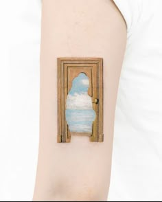 a woman's arm with a painting on it that looks like an open door